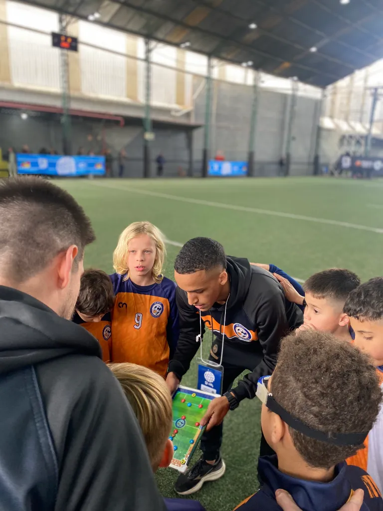 Professor da FM Sport conversando com alunos no campo do HD Sports Complex